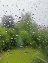 Raindrops on a window in a rainy day, blurry green background Royalty Free Stock Photo