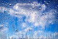 Raindrops on the window. Water drops on glass. Abstract background. Blue sky with clouds. Drops texture. Selective focus Royalty Free Stock Photo