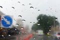 Raindrops on windscreen with defocused road of street cones and signs in background