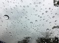 The raindrops on the windscreen or windshield or car glass. View from the inside of the car with a grey sky background. Adjust the Royalty Free Stock Photo