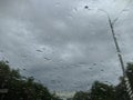 raindrops on the windshield of the car against the background of the sky and trees on the sides.