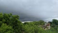 Raining dark cloud over field in big farmland. dramatic rain clouds above the green field and buildings in India Royalty Free Stock Photo