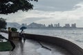 Raining in Park that near the Coast with a Man Holding Umbrella and Seeing Seascape and Cityscape of George Town, Penang, Malaysia Royalty Free Stock Photo