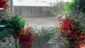 Rainstorm and heavy downpour on rainy day at Christmas. Gloomy weather landscape through tinsel wreathe on Xmas eve