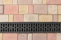 Rainwater drainage system on a sidewalk of colored tiles Royalty Free Stock Photo