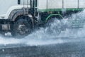 Rainwater spraying from motion truck wheels. city road during he Royalty Free Stock Photo