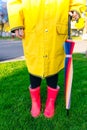 Yellow raincoat. Rubber pink boots against. Conceptual image of legs in boots on green grass Royalty Free Stock Photo