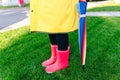 Yellow raincoat. Rubber pink boots against. Conceptual image of legs in boots on green grass Royalty Free Stock Photo