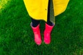 Yellow raincoat. Rubber pink boots against. Conceptual image of legs in boots on green grass Royalty Free Stock Photo