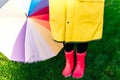 Yellow raincoat. Rubber pink boots against. Conceptual image of legs in boots on green grass. umbrella Royalty Free Stock Photo