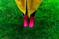 Yellow raincoat. Rubber pink boots against. Conceptual image of legs in boots on green grass Royalty Free Stock Photo