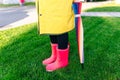 Yellow raincoat. Rubber pink boots against. Conceptual image of legs in boots on green grass. umbrella Royalty Free Stock Photo