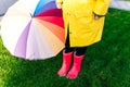 Yellow raincoat. Rubber pink boots against. Conceptual image of legs in boots on green grass. umbrella Royalty Free Stock Photo