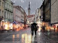 Rainy Autumn street ,people walk with umbrellas evening light blurred on houses and wet pavement in Old Town Of Tallinn travel
