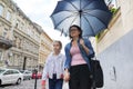 Mother and daughter walking under an umbrella along street Royalty Free Stock Photo