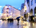 Rainy Christmas city  evening people walking under umbrella evening  street in medieval town  blur light lamp Tallinn old town tra Royalty Free Stock Photo