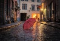 Rainy city street at  evening pink umbrella on wet pavement medieval house street lamp blurred light Royalty Free Stock Photo