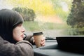 Rainy Day or Bad Weather in a Vacation Concept. a Sadness Woman with Hot Coffee sitting in Car and Looking Outside through Window