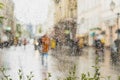 Rainy day in city. People seen through raindrops on glass. Selective focus on the raindrops Royalty Free Stock Photo