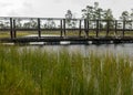 Rainy and gloomy day in the swamp, wooden bridge over the swamp ditch, blurred swamp grass and moss in the foreground, foggy and