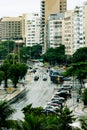 Rainy intersection showing cars and tour buses surrounded by trees apartments, and hotels