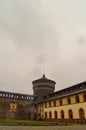 A rainy view of a castle watch tower with clouds and yellow buildings Royalty Free Stock Photo