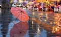 Rainy Weather ,Autumn leaves falling on road , pink umbrella on pavement city night light blurred at evening