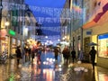 Rainy  weather in the City, Christmas street at night  ,people walking with umbrellas , rain drops reflection on windows vitrines Royalty Free Stock Photo