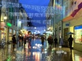 Rainy weather in the City, Christmas street at night ,people walking with umbrellas , rain drops reflection on windows vitrines