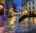 rainy weather city at night black  umbrella on pavement medieval street night blurred light people silhouette in Tallinn old town Royalty Free Stock Photo