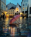 Rainy weather city at night pink umbrella on pavement medieval street night blurred light people silhouette walk under rain in Tal Royalty Free Stock Photo