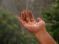 Rainy weather, rain drops falling on womans hand.