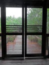 Rainy Wooden Boardwalk Through Screen Door