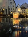 Autumn leaves and  glass  cup with  candle light on table on medieval street evening blurred bokeh light  under rain drops on win Royalty Free Stock Photo