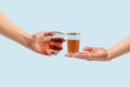 Raise your glass. A celebration where two people toast with a red drink on a pastel blue background. Minimal composition. Toast,