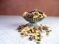 Raised dish filled with trail mix spilling out onto the herringbone counter.  Nuts, almonds, seeds, pumpkin, banana, raisin, Royalty Free Stock Photo
