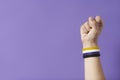 Raised fist of a person wearing a non binary flag bracelet. Gender diversity
