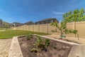 Raised garden beds with plants and soil at the backyard with gravel and grasses