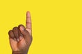 Raised hand asking for permission or answering a question on a yellow background - African ethnicity