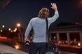 Raised hand to the empty road. Young man with bag trying to stop the car because he`s late