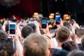 Raised outstretched hands with smartphones photographing stage in the crowd during a concert