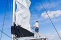 Raising the sail on a yacht. Young man captan lifting the sail of catamaran yacht during cruising Royalty Free Stock Photo