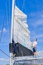 Raising the sail on a yacht. Young man captan lifting the sail of catamaran yacht during cruising Royalty Free Stock Photo