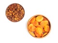 Raisins in clay plate and dried apricot in wooden bowl on white