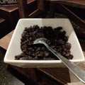 Raisins are served on a white bowl.Raisins are grapes that are dried and can be eaten directly or used in cooking.