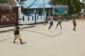 Happy children playing jump rope game on street in poor village