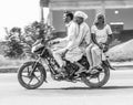 Mother, father and small child riding on scooter through busy highway