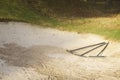 Rake in sand bunker at golf links course green for golfers Royalty Free Stock Photo