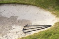 Rake in sand bunker at golf links course green for golfers Royalty Free Stock Photo
