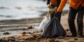 Rake-wielding volunteers clean beach, collecting rubbish in plastic bags.